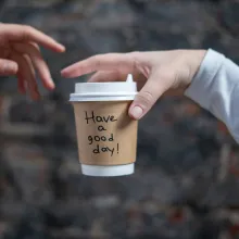 one person giving  cup of coffee to another