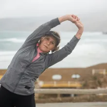 Woman in her 50s stretching arms over head