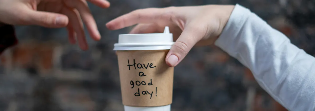 one person giving  cup of coffee to another