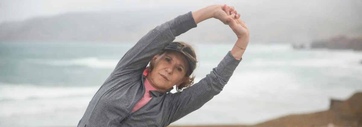 Woman in her 50s stretching arms over head